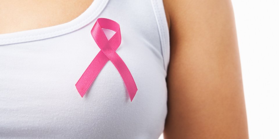 Woman wearing pink ribbon symbolizing early signs of breast cancer awareness