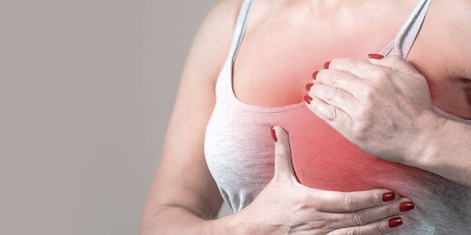 Woman holding her breast with pain, highlighting awareness on Myths and Facts About Breast Cancer.